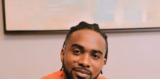 Uzor Arukwe opens up on family’s reaction to his career choice Smiling man in an orange T-shirt sitting on a couch, holding a smartphone toward the camera.