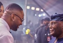 Why I attended BBN’s Cross’ wedding – Atiku Two men greet and smile at an indoor event; one wears a white suit and glasses, the other in traditional blue attire with a head wrap.