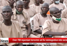700 Ex-Terrorists to Rejoin Society — Nigerians Question Safety and Justice Group of men in beige prison-like outfits seated together, appearing on a news broadcast; red ticker at bottom reads “Over 700 repentant terrorists set for reintegration into society,” with a small timestamp and channel watermark visible.