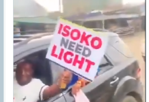 “No Light, No Campaign!” — Edo Youths Protest Ahead of Seyi Tinubu Visit Person leaning out of a car window, holding a sign that reads 'ISOKO NEED LIGHT', likely protesting for electricity.