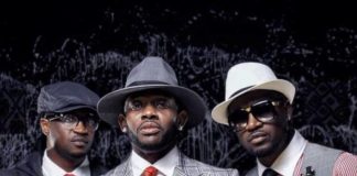 ‘Don’t bring shame on Ndi Igbo,’ J Martins weighs in on Peter, Paul Okoye feud Three men in stylish suits posing for a portrait, wearing hats and sunglasses against a dark backdrop.