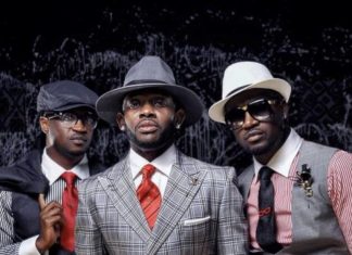 ‘Don’t bring shame on Ndi Igbo,’ J Martins weighs in on Peter, Paul Okoye feud Three men in stylish suits posing for a portrait, wearing hats and sunglasses against a dark backdrop.