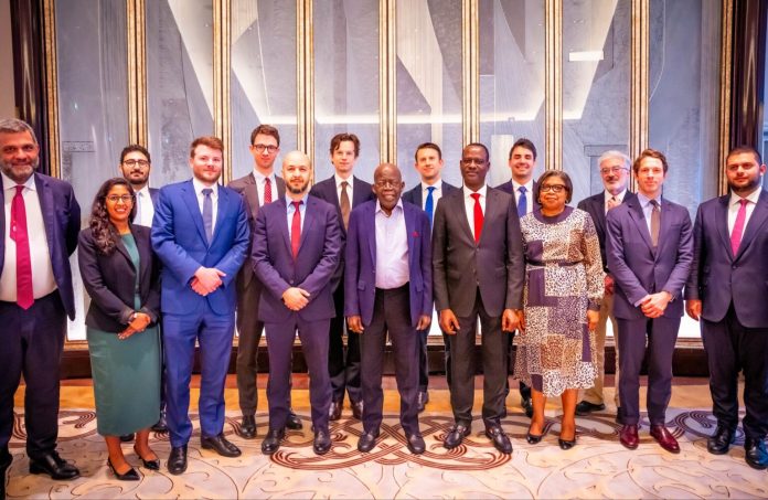Group of diverse professionals in formal attire posing together for a group photo in an elegant lobby with marble wall panels behind them.