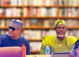Why re-electing Tinubu is a task that must be done – Fani-Kayode, Omokri Two men in colorful traditional outfits sit at a table in a book-lined room; the left man wears blue with sunglasses and a patterned cap, the right wears green with a head wrap.