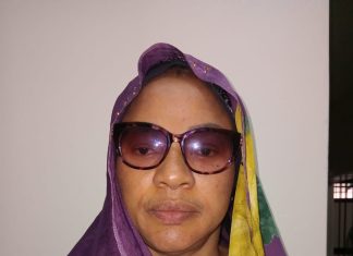 Bank MD docked for alleged N19m, $30,000 fraud Portrait of a woman wearing a purple hijab and a yellow-green patterned scarf, sunglasses, and a neutral expression, facing the camera.