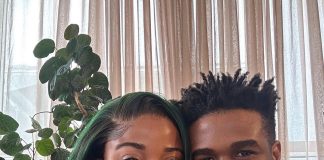 Veekee James, husband welcome baby girl Smiling couple posing for a selfie indoors, with a leafy houseplant in the background and sheer curtains behind them.