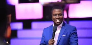 Pastor Bolaji Idowu speaks on infidelity in marriage, forgiveness Smiling man in a blue suit speaks into a microphone at a podium on a lit purple stage.