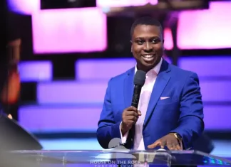 Pastor Bolaji Idowu speaks on infidelity in marriage, forgiveness Smiling man in a blue suit speaks into a microphone at a podium on a lit purple stage.