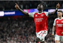Saka sends Arsenal into Champions League final after 20-year wait Two Arsenal players celebrate a goal on the pitch, arms raised, with a cheering stadium crowd in the background.