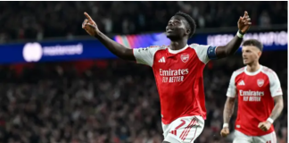 Saka sends Arsenal into Champions League final after 20-year wait Two Arsenal players celebrate a goal on the pitch, arms raised, with a cheering stadium crowd in the background.