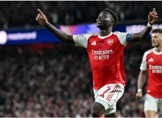 Saka sends Arsenal into Champions League final after 20-year wait Two Arsenal players celebrate a goal on the pitch, arms raised, with a cheering stadium crowd in the background.