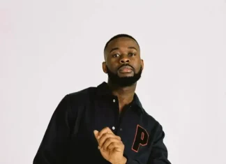 Sarz opens up on how ego affected his career Portrait of a man with a beard wearing a black jacket with a red P patch, looking at the camera.