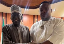 2027: ‘Tinubu doesn’t trust me as an Igbo man’ – Cubana Chief Priest Two men in traditional Nigerian attire shake hands in a formal room, with flags in the background. One wears a dark brown kaftan and cap, the other a white tunic with a gold chain.