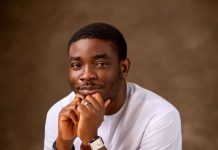 It’s modern slavery- Dolapo Lawal speaks on migration from Nigeria Portrait of a man in a white shirt resting his chin on his folded hands, looking thoughtfully at the camera.