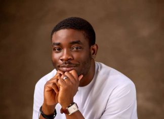 It’s modern slavery- Dolapo Lawal speaks on migration from Nigeria Portrait of a man in a white shirt resting his chin on his folded hands, looking thoughtfully at the camera.