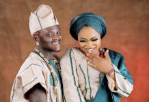 Portable welcomes baby boy with partner Bewaji Happy couple in traditional Nigerian attire: man in beige agbada and cap, woman in teal gele, smiling as she shows her ring.