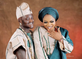 Portable welcomes baby boy with partner Bewaji Happy couple in traditional Nigerian attire: man in beige agbada and cap, woman in teal gele, smiling as she shows her ring.