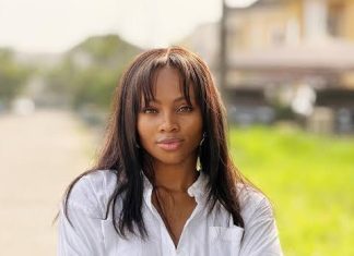 I will not let this slide – Tega Dominic speaks on alleged affair with Frank Edoho Portrait of a woman with long dark hair standing outdoors with arms crossed, wearing a white shirt and a gold watch, looking at the camera.