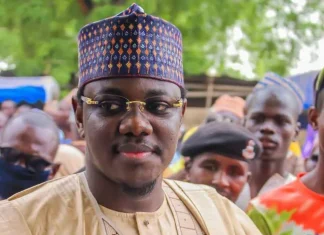 2027: Sule Lamido’s son joins Jigawa governorship race Portrait of a man wearing a patterned traditional cap and glasses at an outdoor gathering.